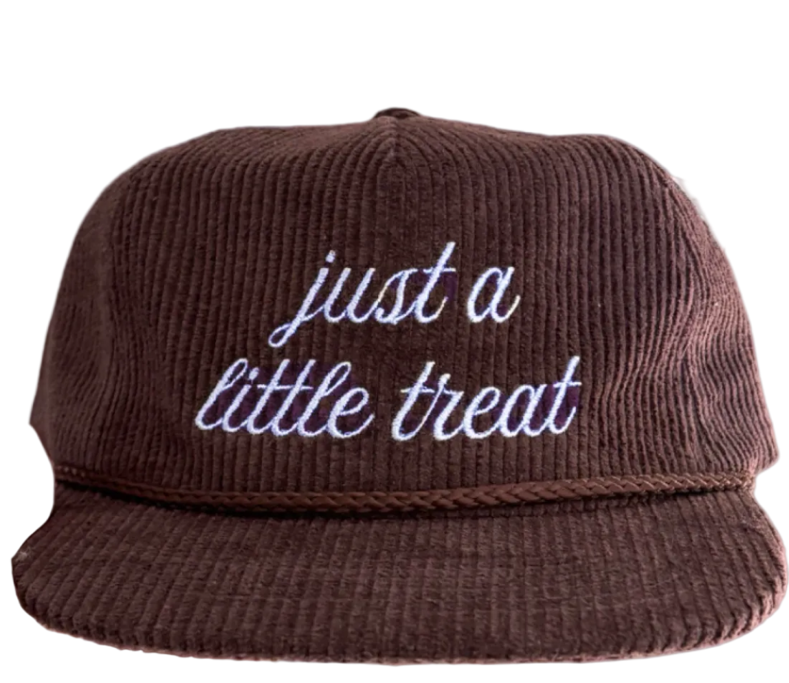 Brown snapback hat with "just a little treat" embroidered on the front in light blue cursive.